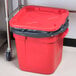 A red Rubbermaid commercial trash can with a black lid.