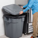 A person opening a Rubbermaid commercial trash can.