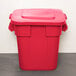 A red Rubbermaid BRUTE trash can with a lid.