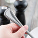 A hand holding a Libbey stainless steel serving spoon.