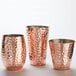 Three American Metalcraft hammered copper Moscow Mule cups with a textured surface.
