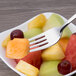 An Arcoroc stainless steel dessert fork holding a piece of fruit.