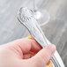 A hand holding a Libbey stainless steel dessert fork.