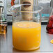An American Metalcraft glass beaker filled with orange liquid on a counter.
