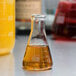 An American Metalcraft Erlenmeyer flask filled with yellow liquid.