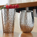 Two silver American Metalcraft hammered stainless steel Moscow Mule cups on a table with berries.