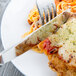 A Libbey Aspire dinner knife and fork on a plate of food with chicken and spaghetti.