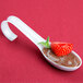 A Fineline Tiny Temptations white plastic spoon with chocolate spread and a strawberry on it.