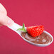 A Fineline white plastic spoon with a spoonful of chocolate pudding and a strawberry on top.