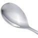 An Arcoroc stainless steel demitasse spoon with a white handle.