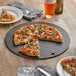 A pizza on an Epicurean slate wood fiber pizza board with a slice cut on the side.