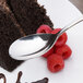 An Arcoroc stainless steel dessert spoon on a plate with a piece of chocolate cake and raspberries.