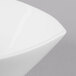 A close up of a Schonwald white square porcelain bowl with a curved edge.