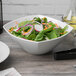 A Schonwald white square porcelain bowl filled with salad on a table.