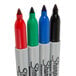 A group of Sharpie fine tip permanent markers in assorted colors including blue, green, red, and black tubes.