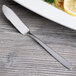 An Arcoroc stainless steel fish knife on a plate with a lemon slice.