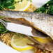 An Arcoroc stainless steel fish knife on a plate of fish with rice and lemons.