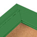 The green corner of an Aarco indoor bulletin board cabinet with a cork board inside.
