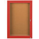 A red framed Aarco bulletin board cabinet with a hinged locking door.