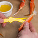 A person using a yellow Choice Shuckaneer pliers to open a crab claw.
