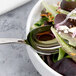 An Arcoroc stainless steel serving spoon in a bowl of salad.