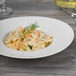 A Schonwald white porcelain bowl filled with pasta and a sprig of rosemary.