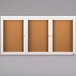 A white Aarco bulletin board cabinet with three cork boards inside.