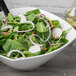 A Schonwald continental white square porcelain bowl filled with salad with spinach, radishes, and onions.