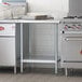 A Regency stainless steel work table with undershelf in a commercial kitchen.