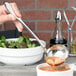 A Chef & Sommelier stainless steel ladle pouring soup into a bowl.