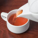 A Schonwald white porcelain teapot pouring tea into a white cup.