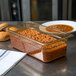 A Carlisle amber plastic food pan filled with baked beans on a table.
