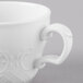 A close-up of a Schonwald white porcelain tea cup with a decorative design and white liquid inside.