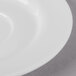 A close-up of a Schonwald white porcelain espresso saucer with a rim.