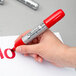 A person holding a Sharpie King Size red permanent marker over a piece of paper with the word "no" written in red.