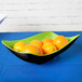 A group of oranges in a green and black GET Brasilia melamine bowl.