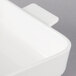 A close-up of a white square serving dish with a lid.