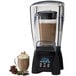 A Waring commercial blender with a glass mug of hot chocolate and a glass of coffee.