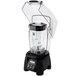 A black Waring commercial blender with clear container on a counter.