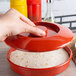 A hand using a Thunder Group Nustone red deep divided server lid to cover a tortilla in a red container.