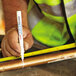 A person measuring a pipe with a white Uni-Paint fine point marker.