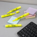 A black keyboard and a group of Sharpie yellow highlighters.