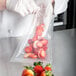 A person in gloves vacuum sealing a bag of strawberries.
