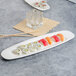 A Villeroy & Boch white porcelain oval platter with sushi and chopsticks on a table.