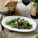 A Villeroy & Boch white porcelain oval platter with green beans, cranberries, and grapes on a table.
