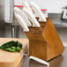 A Dexter-Russell slant knife block with white handles holding knives.