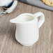 A close up of a white Villeroy & Boch porcelain creamer on a table.