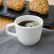 A white Villeroy & Boch porcelain cup filled with coffee on a table with croissants.