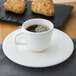 A Villeroy & Boch white porcelain cup of coffee on a saucer next to a croissant.