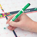 A hand holding a green Expo fine point dry erase marker.